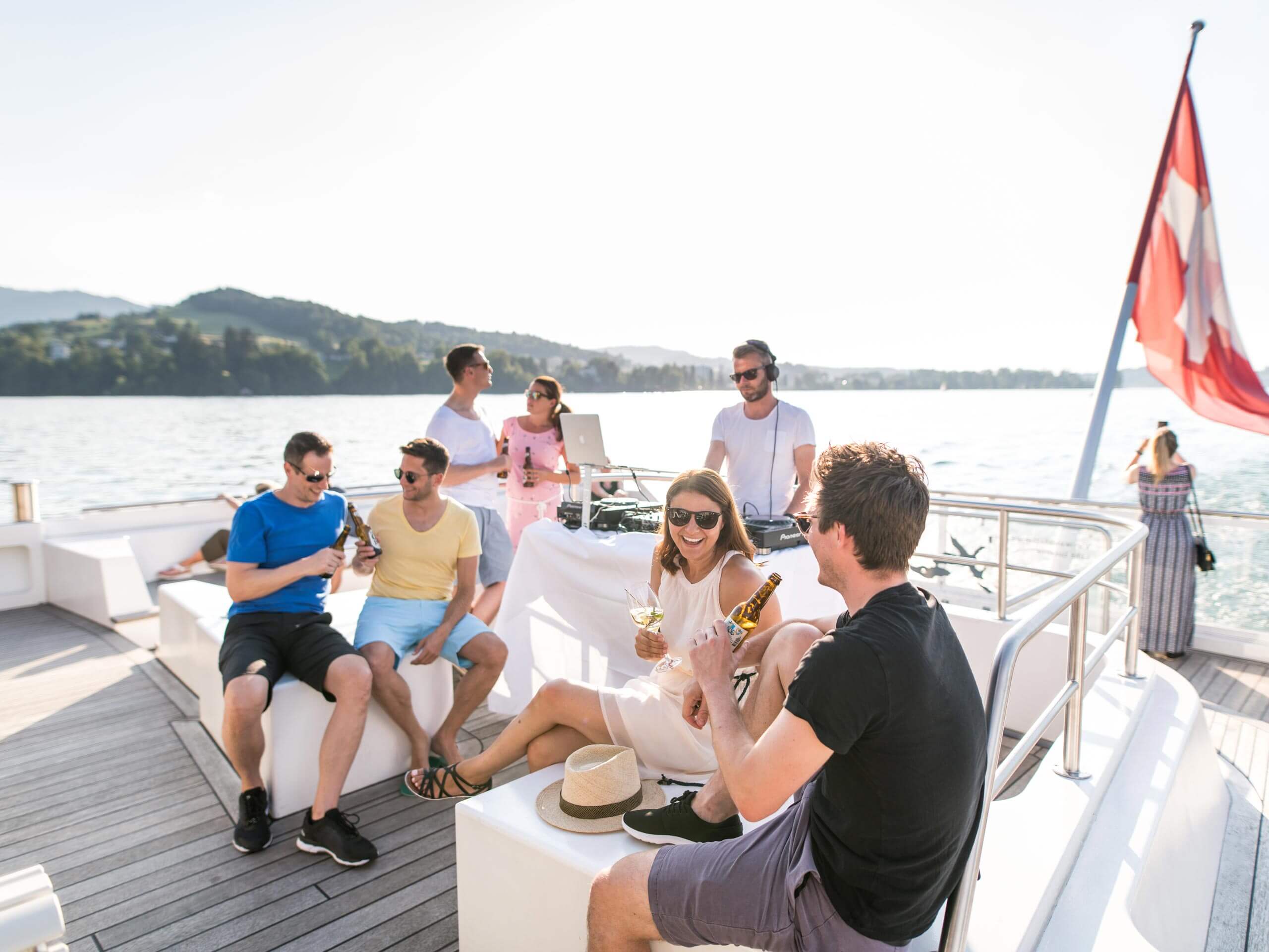 Personen feiern bei einer Schifffahrt über den Vierwaldstättersee und stossen mit Urbräu an.